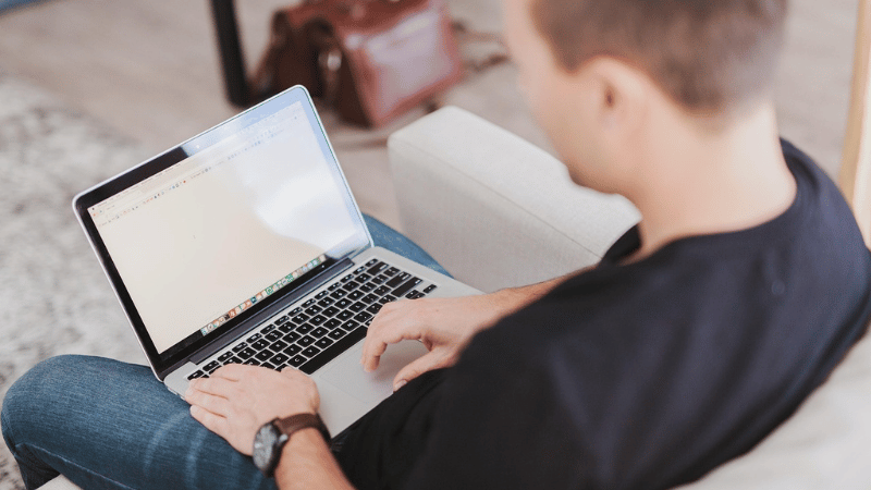 ソファに座ってパソコンを開く男性