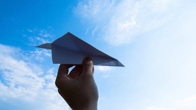 紙飛行機を飛ばす手