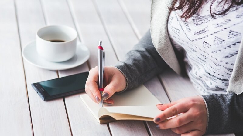 自分の適性をより明確にするためメモを取る女性の画像