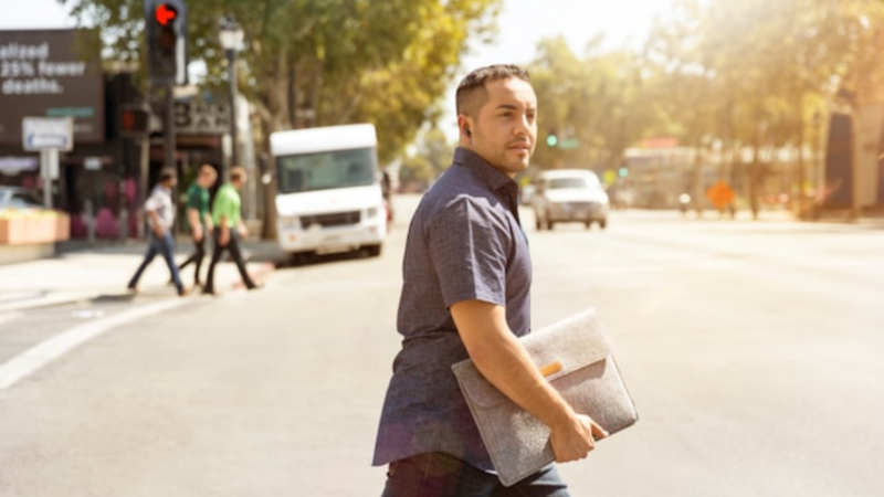 クラッチバックを持って道路を渡ろうとしている男性