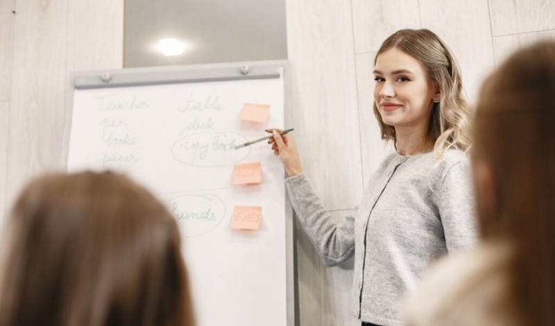 ホワイトボードを指しながら説明している女性