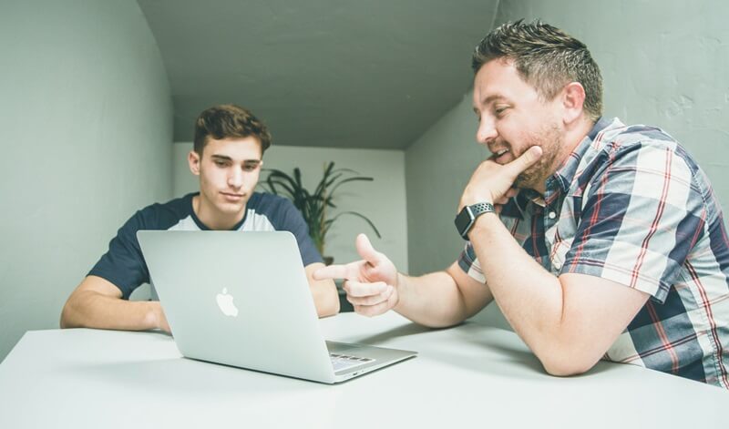 パソコンを見ながら会話をしている2人の男性