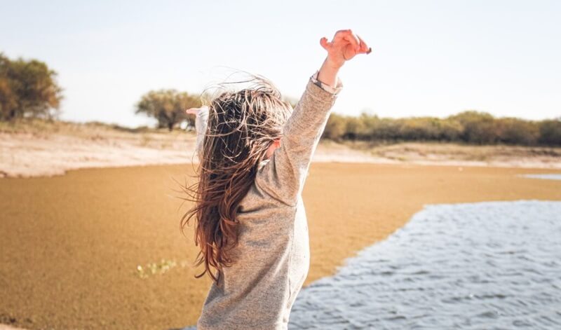 海に向かってバンザイしている女性