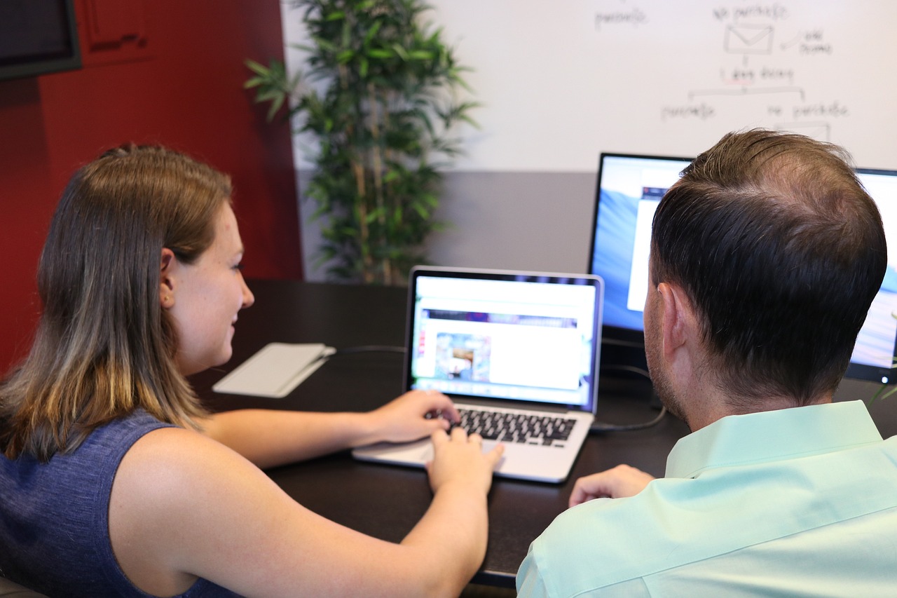 パソコンを操作している女性と隣で教えている男性