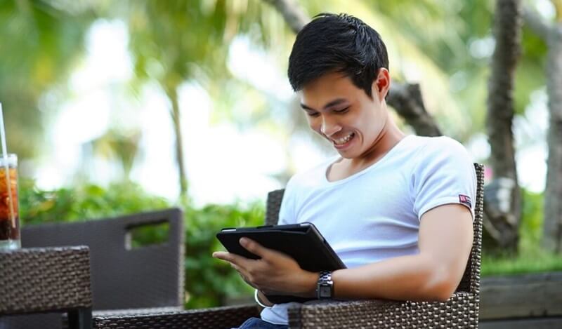 テラス席でタブレットを見ながら笑顔を見せる男性