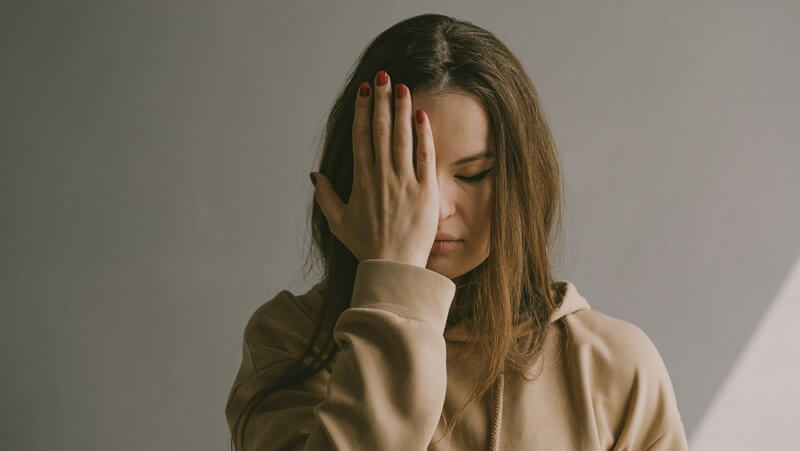右手を顔に当て悩んでいる女性