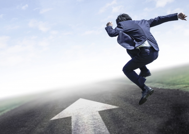 矢印に向かってジャンプするスーツの男性