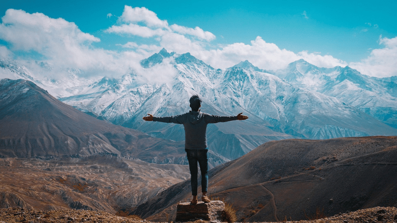 山脈に向かって両手を広げている男性