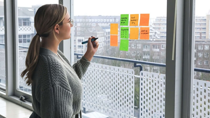 窓に付箋を貼ってメモする女性