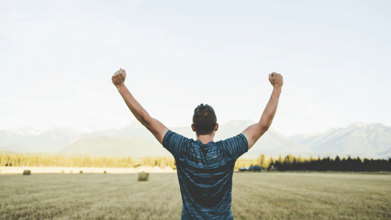 空に向かって両手を上げている男性