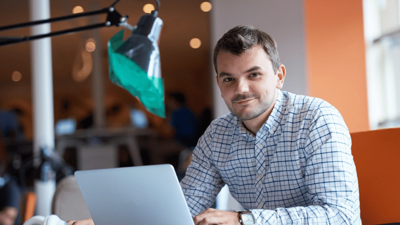 パソコンで仕事をしながら微笑む男性