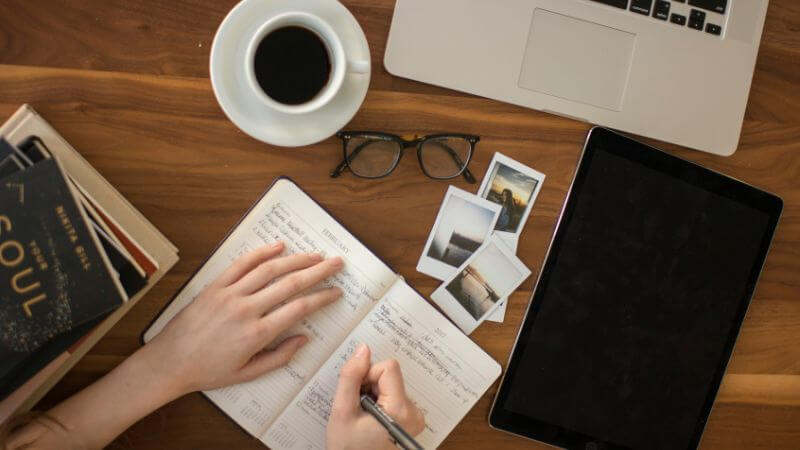 コーヒーとノートに何かを書いている