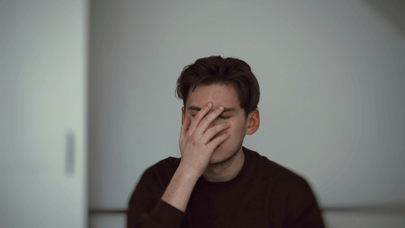 手で顔を覆う男性