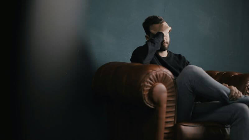 椅子に座り悩む男性
